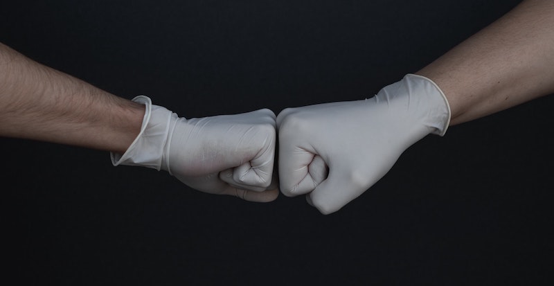 Hands with plastic gloves fist bumping